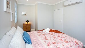 Een slaapkamer met een bed, een bedlamp, een kledingkast en een airconditioning.
