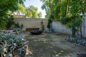 Un jardín con un pozo de fuego, escalones de piedra y una valla de madera.