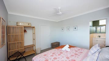 A bedroom with a bed, a wardrobe, a ceiling fan, and a bathroom visible through an open door.