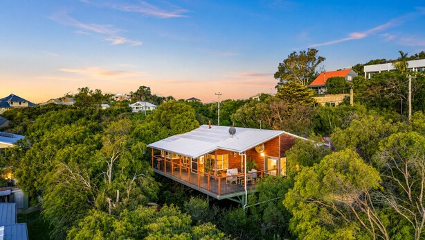 A modern house with a deck, surrounded by dense greenery. - Yarrimbah Holiday Retreat  (Peppermint Grove Beach)