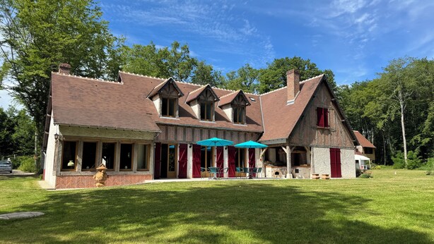 A two-story building with a brick facade, multiple windows, and a covered patio area with outdoor seating. - Grand Siècle Room in Sologne (Mont-près-Chambord)