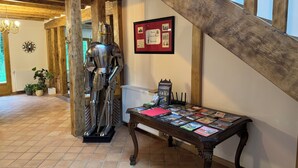 A medieval knight statue, a wooden staircase, and a table with postcards. - Grand Siècle Room in Sologne (Mont-près-Chambord)