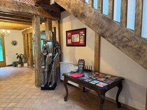 Eine Ritterstatue im mittelalterlichen Stil, eine Holztreppe und ein Tisch mit Postkarten.