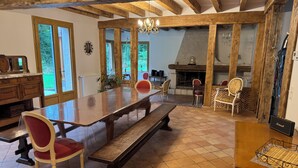 A spacious dining area with a long wooden table, red upholstered chairs, and a fireplace. - Grand Siècle Room in Sologne (Mont-près-Chambord)