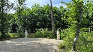A gravel path leading through a wooded area with two statues. - Grand Siècle Room in Sologne (Mont-près-Chambord)