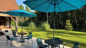 An outdoor patio with a brick fireplace, green chairs, and a round table. - Grand Siècle Room in Sologne (Mont-près-Chambord)