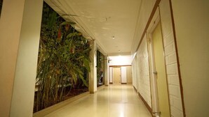 A hallway with a plant wall, a door on the right, and a light fixture on the ceiling. - Vihar Holiday Resorts (Araku Valley)