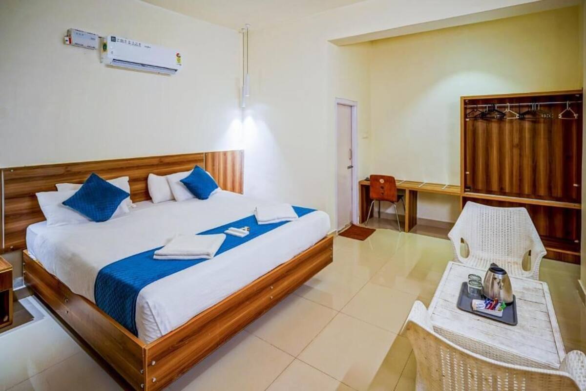 A hotel room with a wooden bed, a desk, a chair, and a wardrobe.