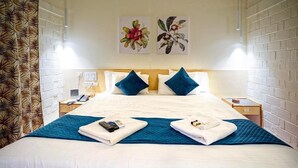 A hotel room with a large bed, two pillows, a blue blanket, and two towels folded on the bed. There are two paintings on the wall above the bed. - Vihar Holiday Resorts (Araku Valley)