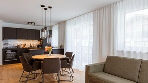 A modern kitchen with dark cabinets, a wooden dining table, and pendant lights. - Exclusive Apartment With Terrace (Fiss)