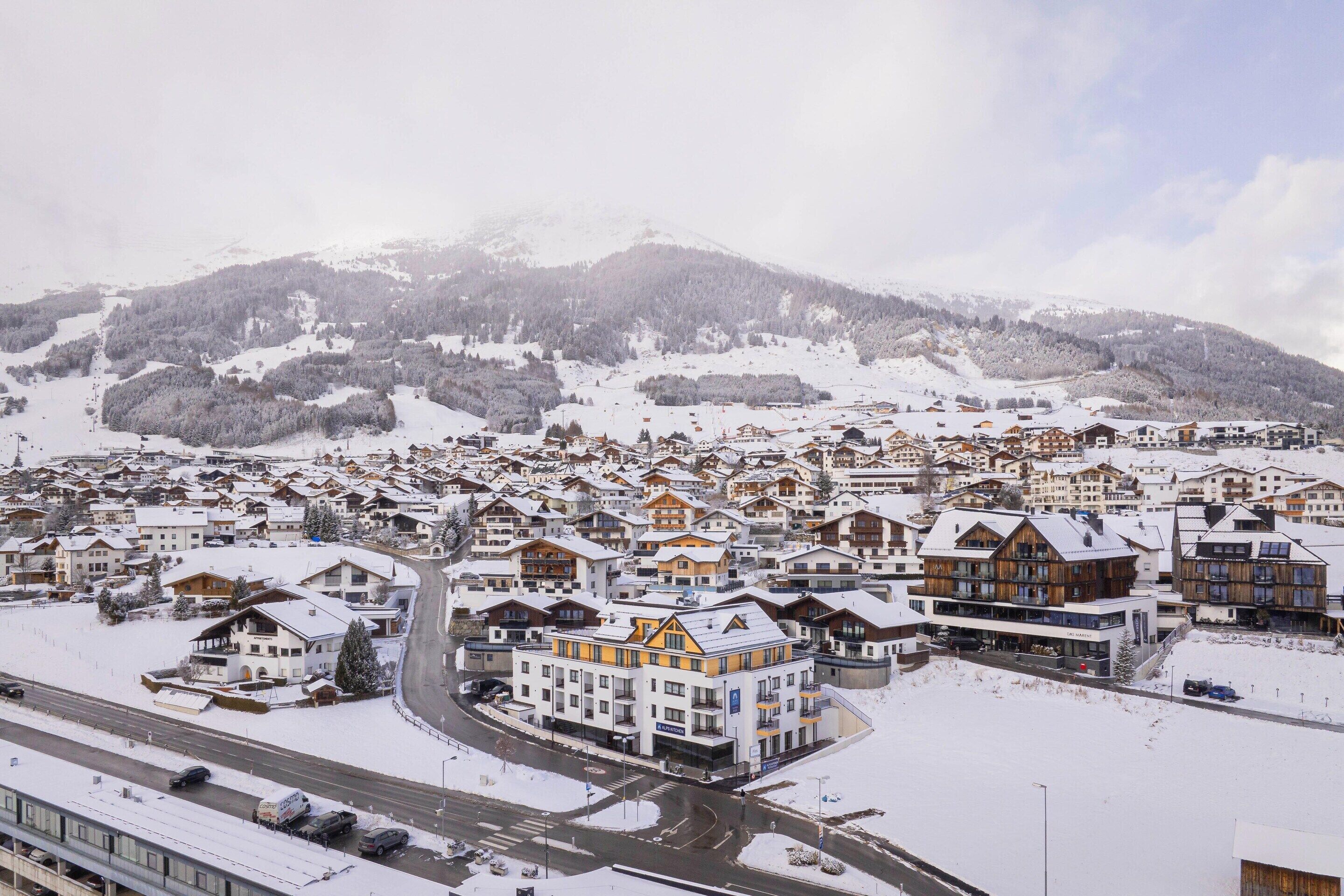 A snow-covered town with a mix of traditional and modern buildings, including a prominent hotel with a large sign.