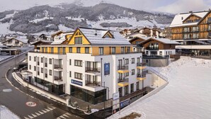 A modern hotel with multiple floors, balconies, and a ski resort backdrop. - Exclusive Apartment With Terrace (Fiss)