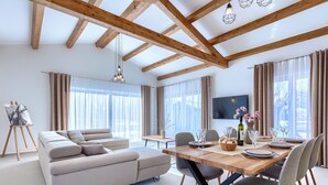 A modern living room with a sofa, dining table, and chairs. There is a painting on easel, a TV mounted on the wall, and large windows with curtains. - Jolanda by Interhome (Rovinj/Žminj)