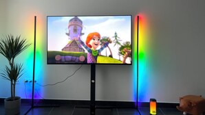 A television mounted on a wall with a colorful LED light strip on either side.