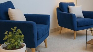 Two blue armchairs with white cushions, a small potted plant, and a glass coffee table with chess pieces. - Hotel Ana Isabel (Zamora)