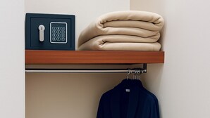 A bathroom with a towel rack, a robe hanging, and a folded towel on a shelf. - Hotel Ana Isabel (Zamora)