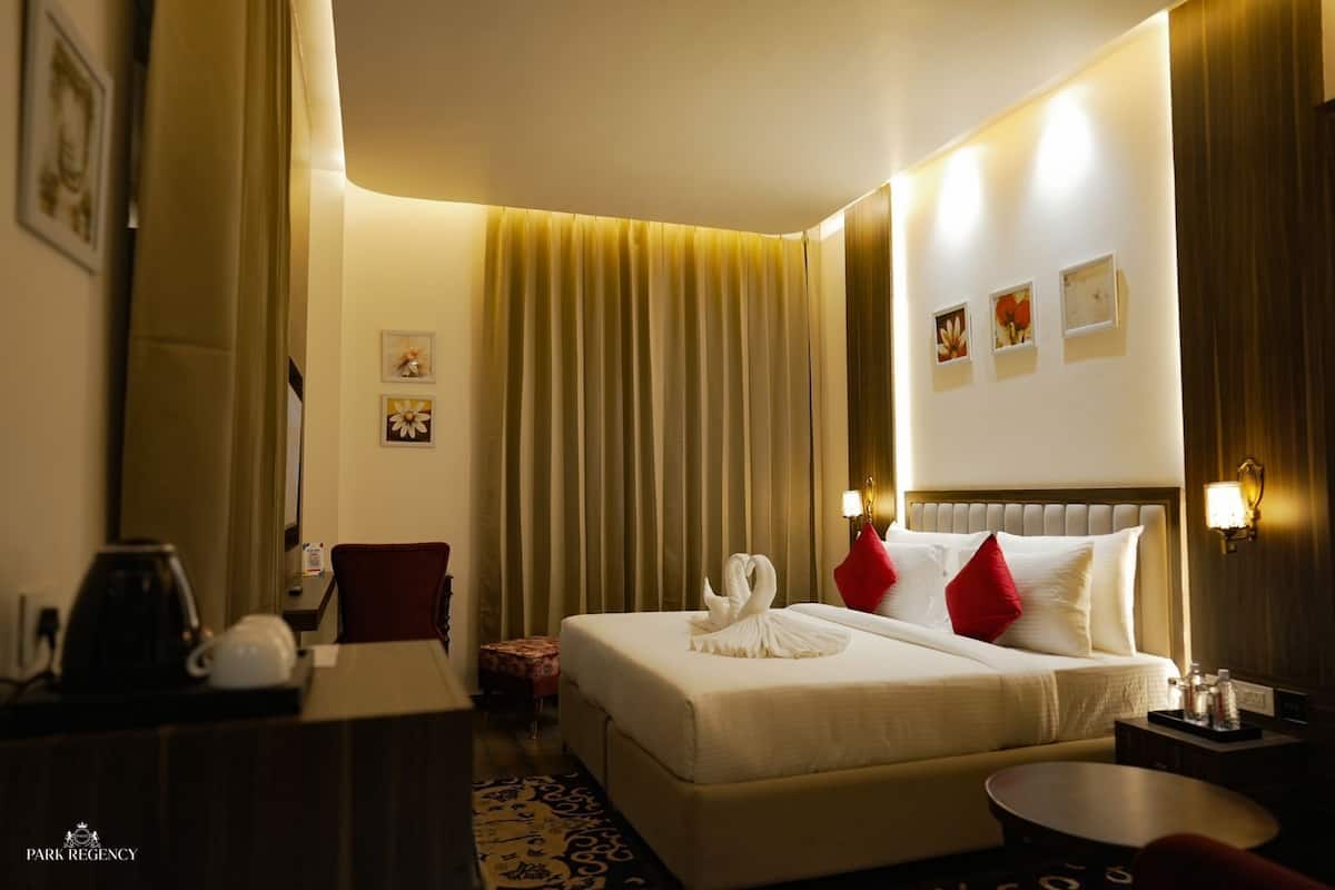 A hotel room with a bed, a desk, a chair, and a small table.