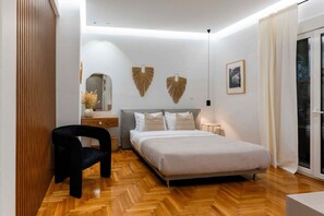 A modern bedroom with a bed, a chair, a bedside table, and a large window with curtains.