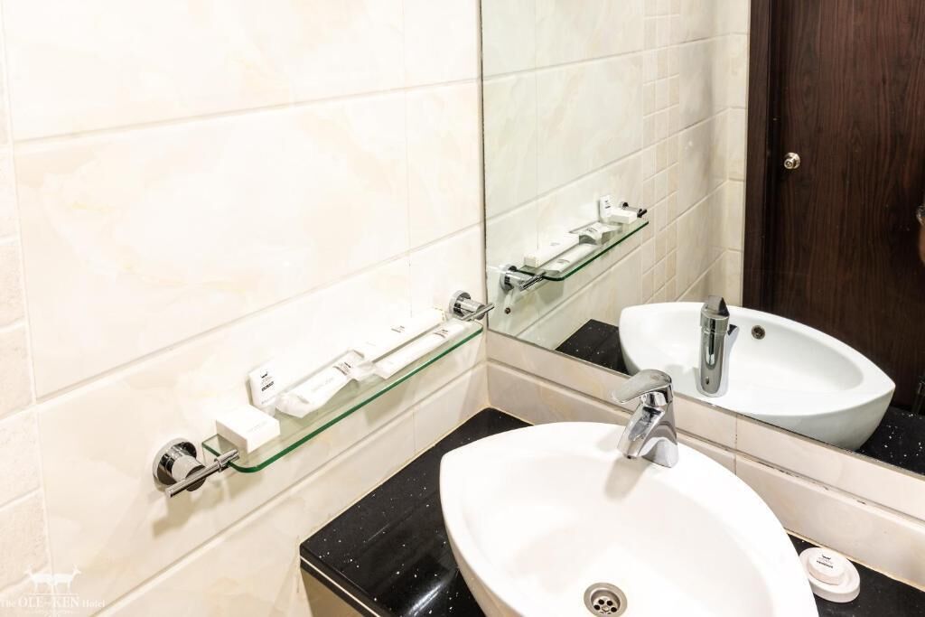 A bathroom with a white sink, a glass shelf, and a mirror.