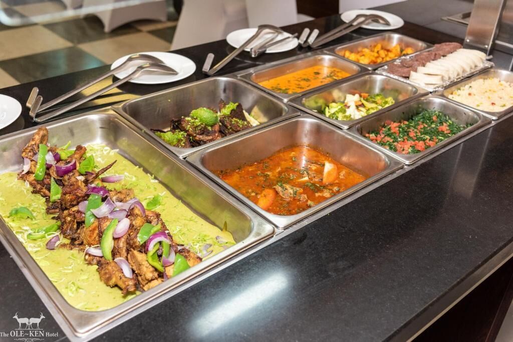 Un bufé con diversos platos, incluyendo salsa verde con carne, salsa roja con verduras y otras preparaciones variadas.