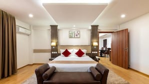 A hotel room with a large bed, a brown leather sofa, a desk, and a dining area. - The Ole-Ken Hotel (Nakuru)