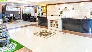 A hotel reception area with a reception desk, seating area, and decorative elements like a fountain and wall art. - The Ole-Ken Hotel (Nakuru)