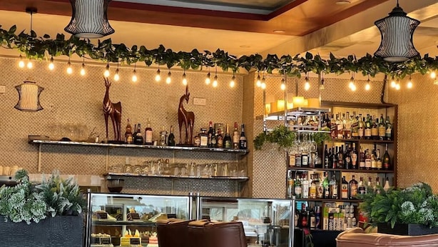 A bar area with a glass display case, leather seating, and a variety of bottles on shelves. - The Ole-Ken Hotel (Nakuru)