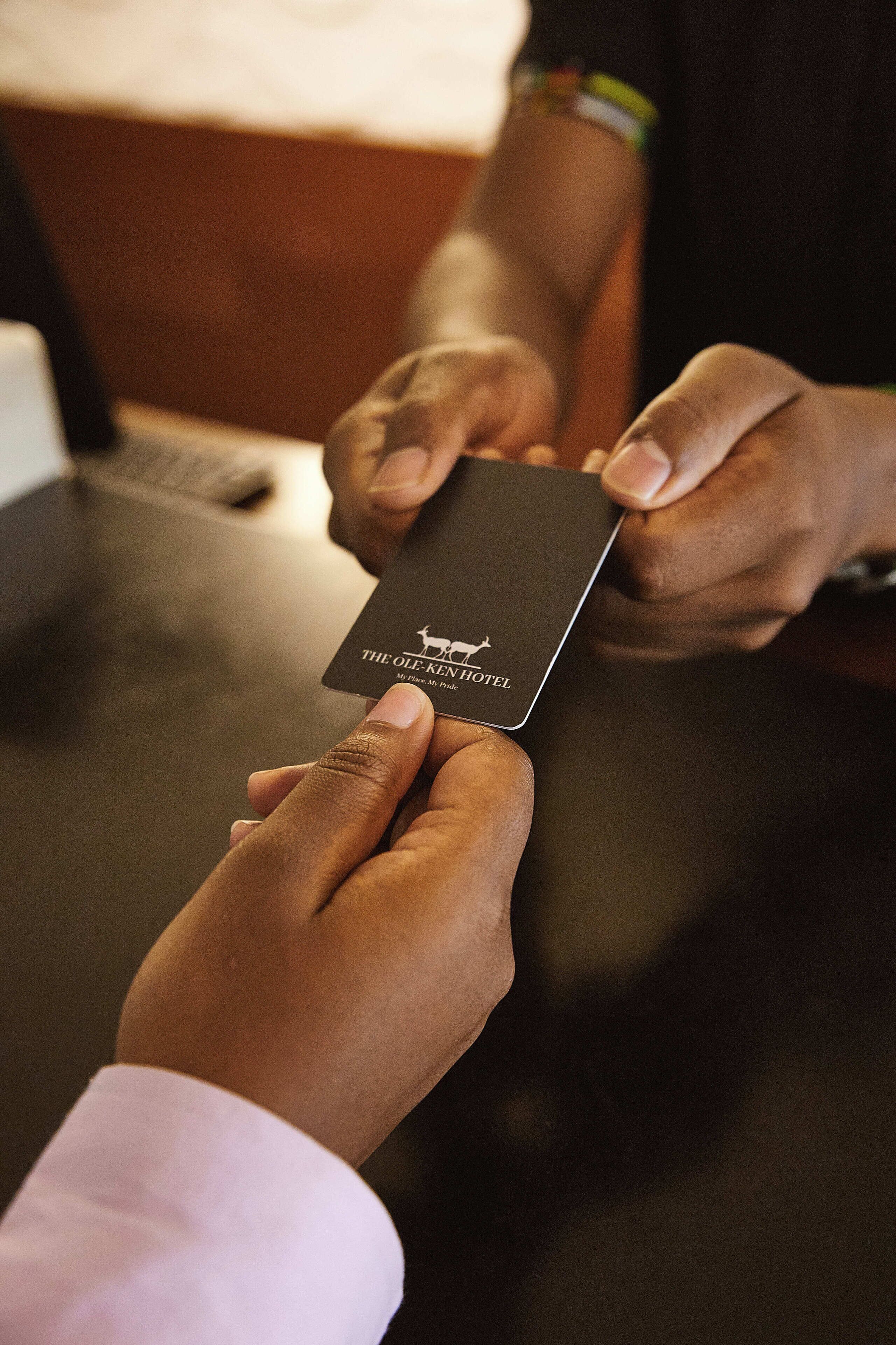 Una persona sosteniendo una tarjeta negra con la inscripción 'The Ole Kang Hotel'.