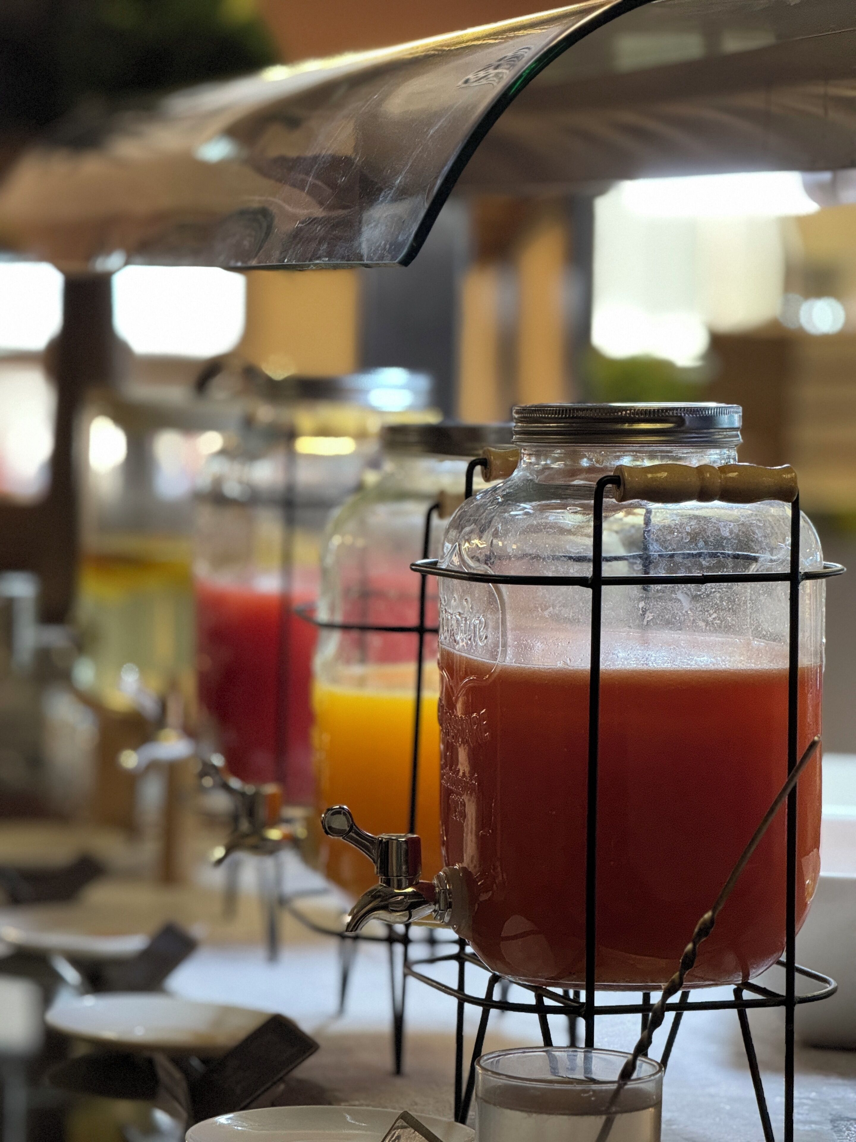 Estación de bebidas con varios dispensadores, incluyendo una bebida roja y una bebida transparente con hielo.