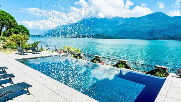 A swimming pool with clear water, surrounded by lounge chairs and a view of a lake and mountains. - Lago Infinito by Interhome (Gravedona)