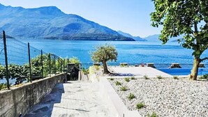 A pathway leading to a lakeside area with a view of mountains in the background. - Lago Infinito by Interhome (Gravedona)