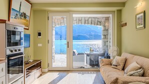 A cozy living room with a large sliding glass door leading to a balcony overlooking a scenic body of water. - Riflesso del lago by Interhome (Gravedona)