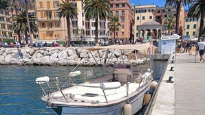 A boat docked at a marina with a stone wall and buildings in the background. - Casa Rosa al Mare, Rapallo (Rapallo)
