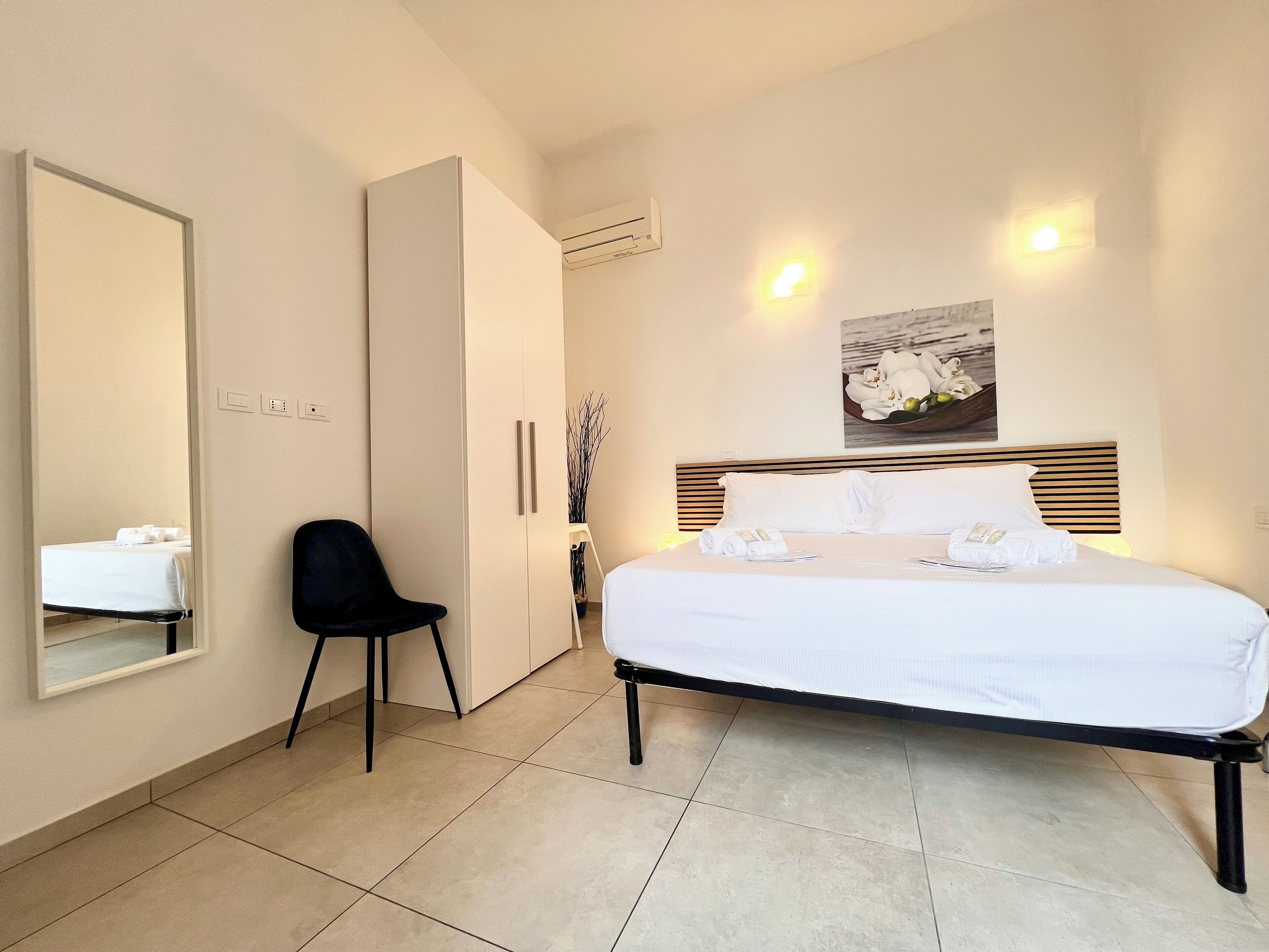 Ein Hotelzimmer mit einem Bett, einem Sessel, einem Kleiderschrank und einem Spiegel.