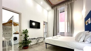 A hotel room with a bed, a TV, a washing machine, and a drying rack. - Casa Rosa al Mare, Rapallo (Rapallo)