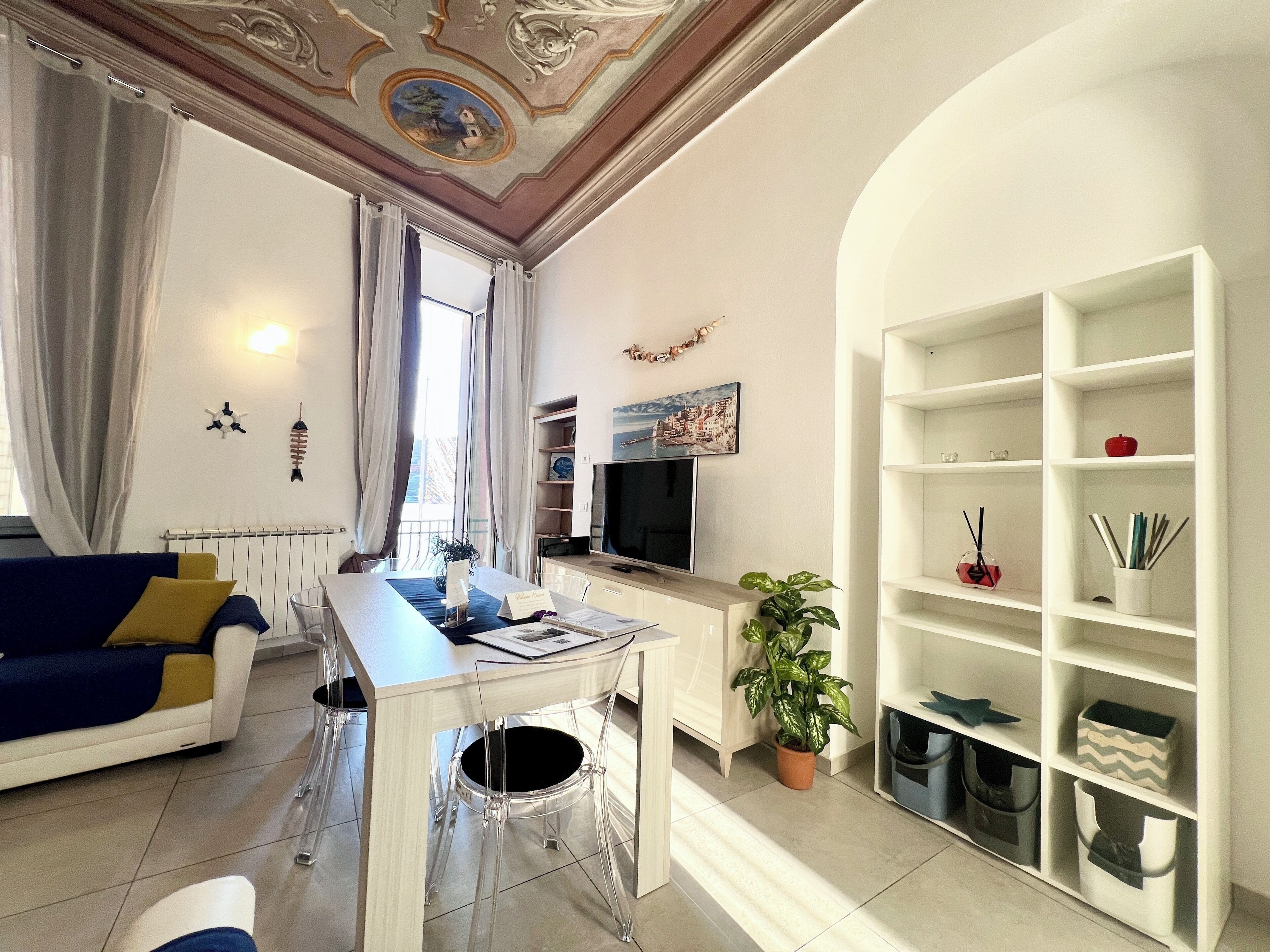 Un salon moderne comprenant un canapé, une table à manger, un téléviseur et une bibliothèque.