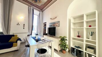 Un salon moderne comprenant un canapé, une table à manger, un téléviseur et une bibliothèque.