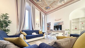 A living room with a sofa, a dining table, and chairs. There is a TV and a bookshelf in the room. - Casa Rosa al Mare, Rapallo (Rapallo)