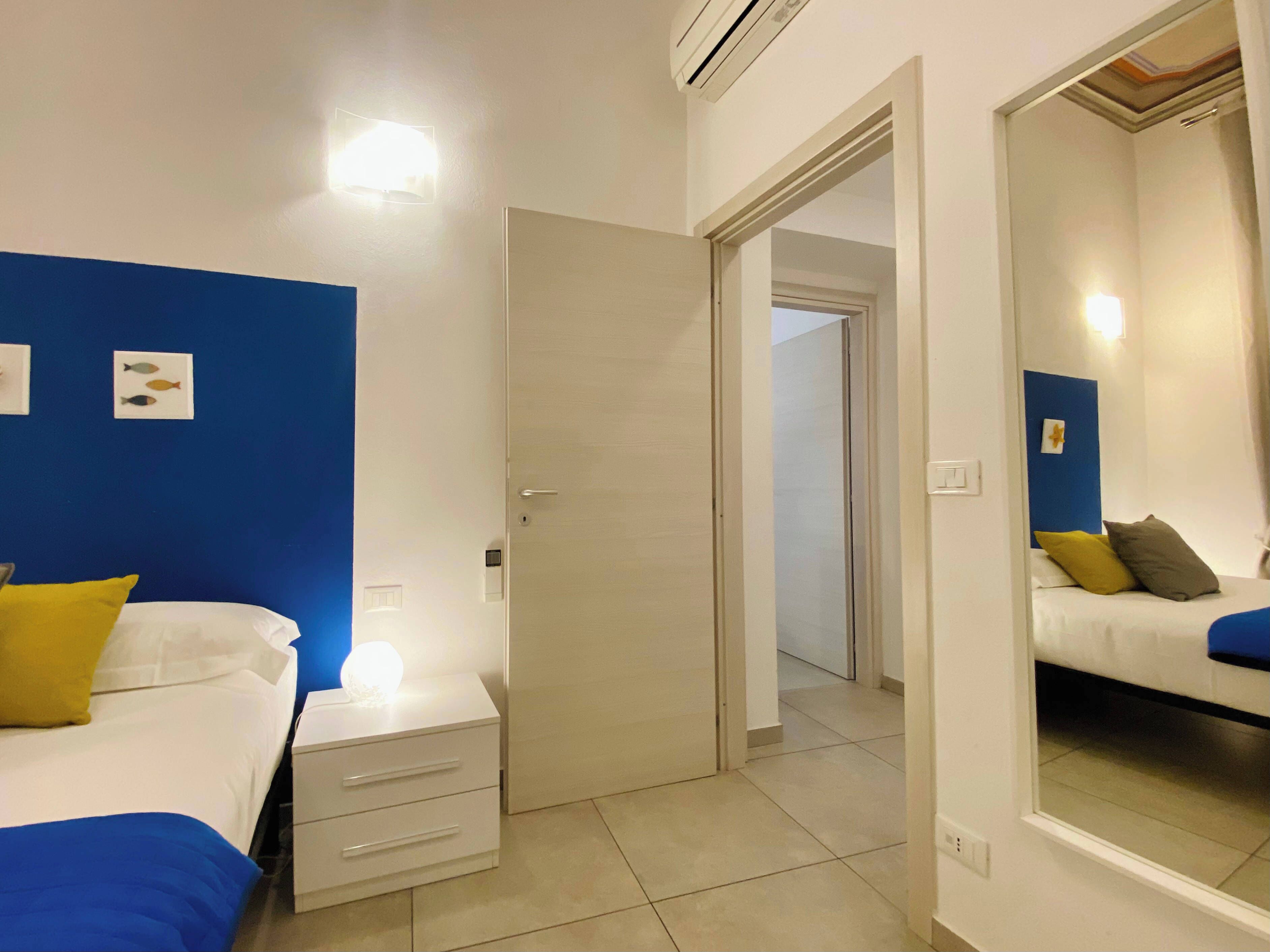 Ein Hotelzimmer mit zwei Betten, einem Nachttisch, einem Spiegel und einer Tür zu einem anderen Raum.