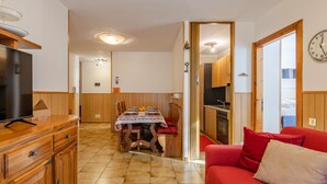 Un espacio habitable compacto con comedor, kitchenette y un sofá rojo.