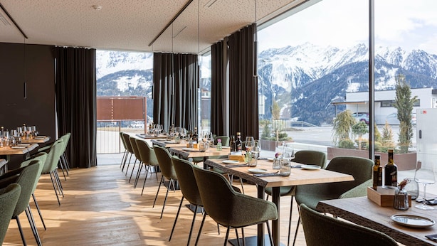 Un espace repas avec des tables dressées pour le service, de grandes fenêtres offrant une vue sur les montagnes et un aménagement intérieur moderne.