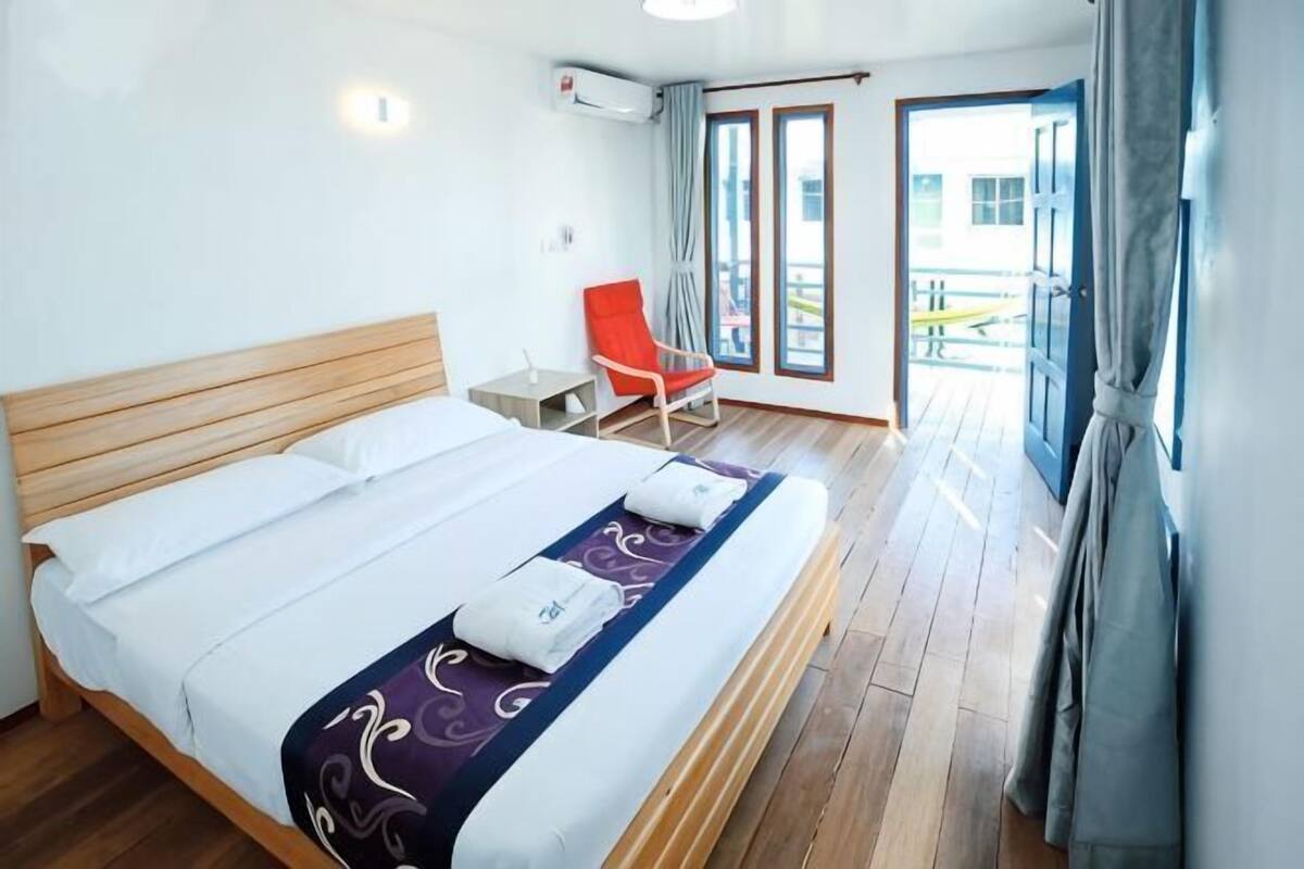 A hotel room with a bed, a chair, and a view of the outside.