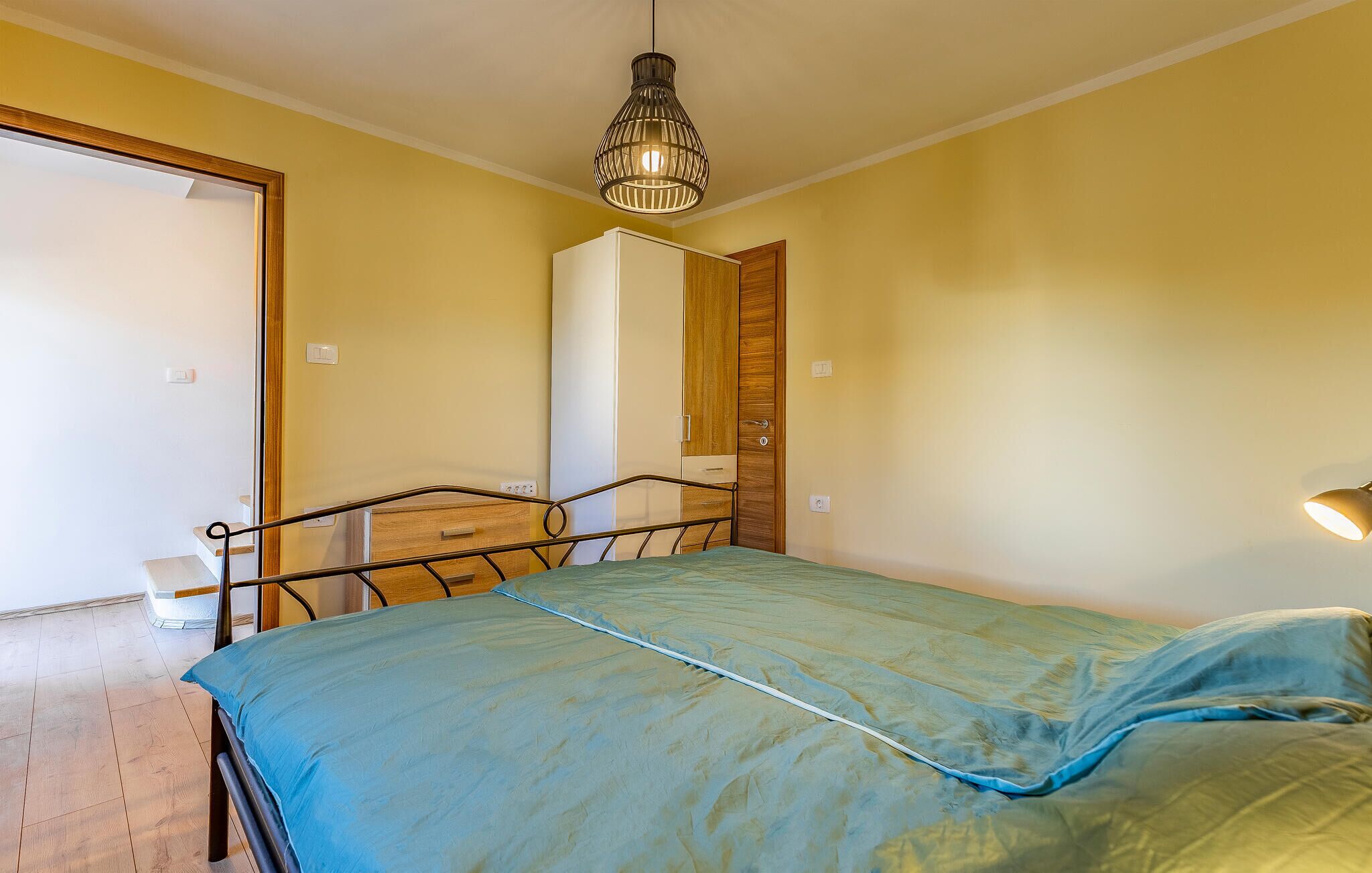 Ein Schlafzimmer mit Bett, Kleiderschrank, Schminktisch und einer Pendelleuchte.