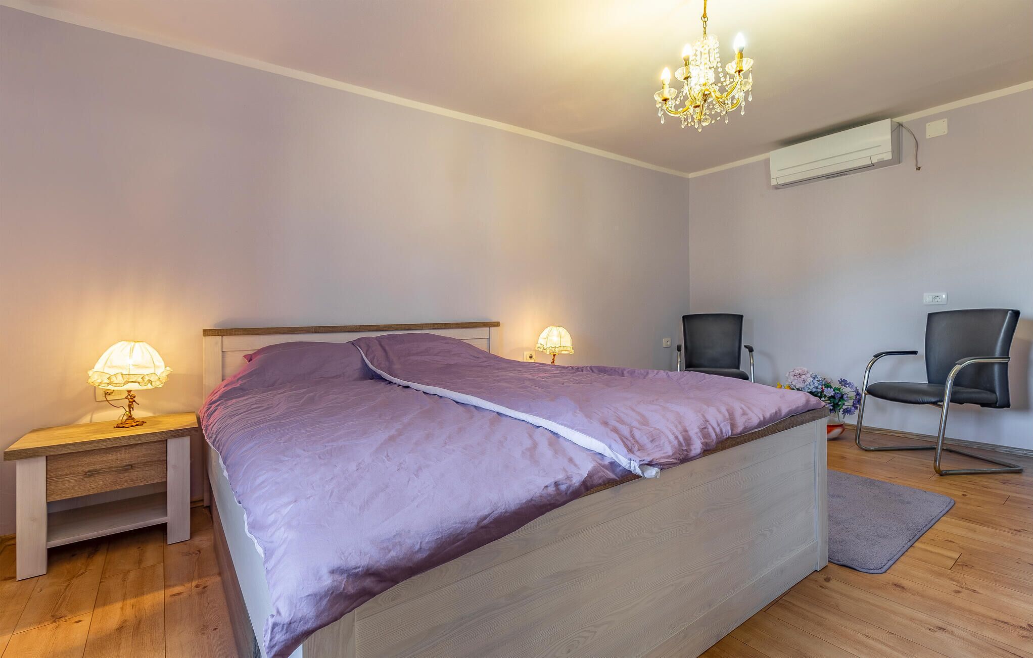 Ein Schlafzimmer mit einem Bett, Nachttischlampen, einem Sessel und einer Kandelaber.