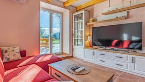 A cozy living room with a red sofa, a wooden coffee table, and a large flat-screen TV.