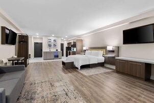 Una habitación de hotel moderna con cama, televisor, escritorio y zona de estar.