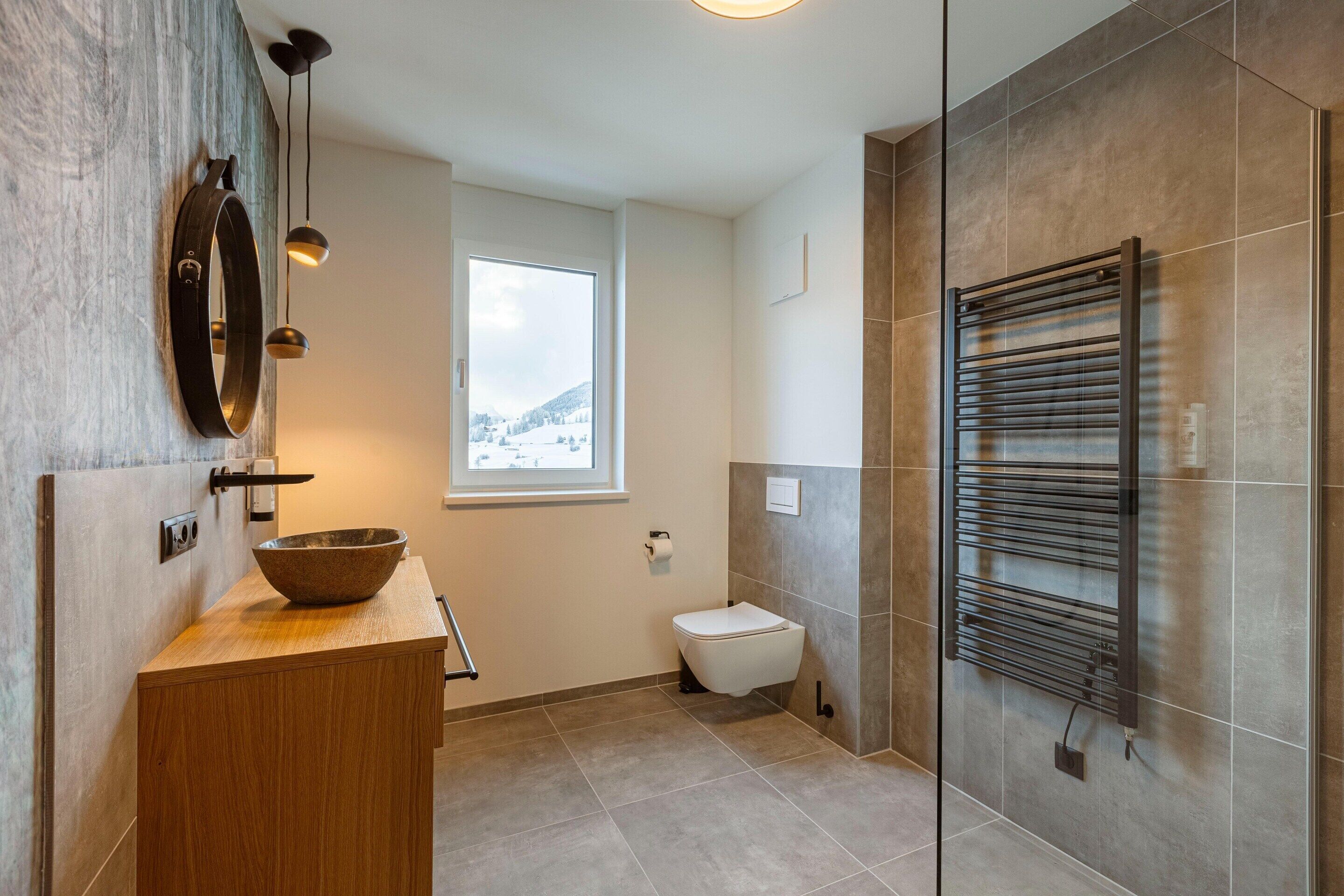 Un baño moderno con tocador de madera, lavabo, inodoro y perchero para toallas.