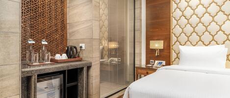 Quarto de hotel com uma cama, um minibar, uma lareira protegida por vidro, um divisório de madeira e um painel de parede estampado.