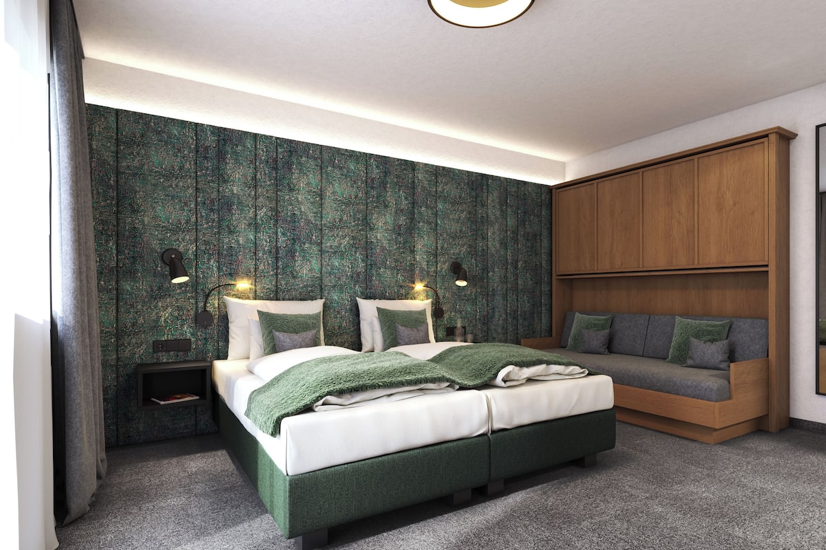 A modern bedroom with a bed, bedside tables, a sofa, and a wardrobe.