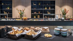 Un bufé con panes, pasteles y una selección de bebidas.
